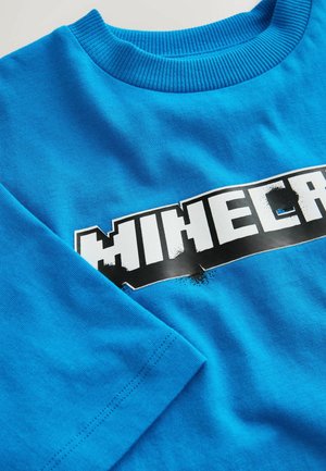 Leuchtend blaues Langarmshirt mit geripptem Rundhalsausschnitt und teilweise sichtbarem, weißem und schwarzem Minecraft-Logo auf der Brust.