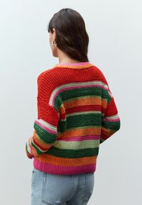 Flerfärgad stickad tröja med horisontella ränder i röd, grön, orange och rosa. Lös passform med ribbade ärmslut och nederkant.