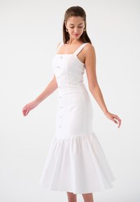 Robe blanche avec un corsage ajusté, décolleté carré et détail de boutons. L'ourlet évasé ajoute du volume. Réalisée en tissu lisse et léger.