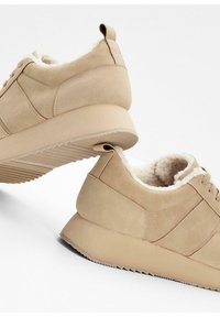 Baskets en suède beige avec une finition texturée, doublure douce, bout rond et semelle en caoutchouc striée. Comprend un système de laçage et une tirette.