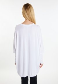 Witte oversized trui met lange mouwen, ronde halslijn en een losse pasvorm, gemaakt van zachte stof, met een effen textuur.