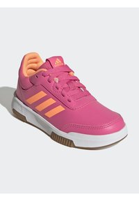Scarpa sportiva rosa con dettagli arancioni, materiale sintetico testurizzato, tre strisce bianche su un lato e suola in gomma bianca con battistrada marrone.