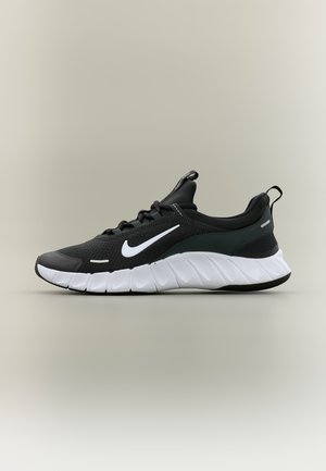 Melnā Nike skriešanas apava ar baltu Swoosh logotipu un biezām baltām zolēm, attēlots uz gaiša neitrāla fona, sānskats.