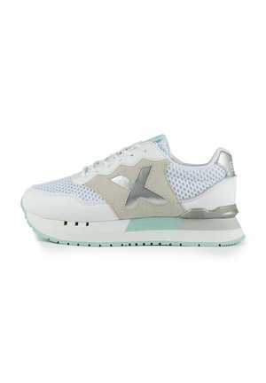 Zapatilla deportiva blanca con parte superior de malla, acentos de ante, logo plateado y suela verde menta. Presenta un cierre con cordones y detalles texturizados.