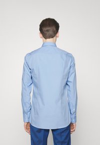 Lichtblauwe button-up shirt met een gestructureerde kraag, lange mouwen en zacht katoenen stof. Heeft een afgeronde zoom en subtiele stikdetails.