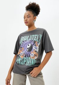 Szare, oversize'owe T-shirty z kolorową grafiką słońca i symbolu yin-yang, z kwiatowymi akcentami oraz wyraźnym napisem "Absolutnie inspirujące."