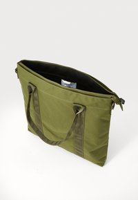 Olijfgroene tote bag met dubbele handvatten, gemaakt van duurzame stof, met een ritsafsluiting en een zwarte voering.
