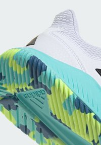 Chaussure de sport blanche avec semelle multicolore texturée en sarcelle, jaune et bleu marine, avec logo Adidas au centre de la semelle.