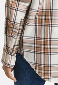 Katoenen geruite shirt in bruin, crème en grijs. Opvallende knoopdetails op de mouw en een gebogen zoomontwerp.