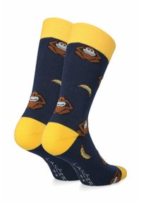 Niebieskie skarpety z żółtymi mankietami i podeszwami, zdobione powtarzającym się wzorem z kreskówkowym małpą i bananami. Wykonane z miękkiego materiału, z trwałym szyciem.