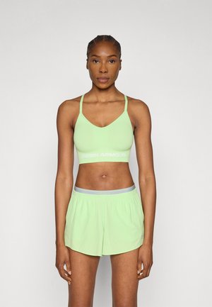 Lichtgroene sportbeha met dunne bandjes en een witte "UNDER ARMOUR"-logo. Gecombineerd met bijpassende lichtgroene shorts met een grijze tailleband.