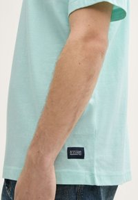 Lyseblå bomulds-T-shirt med korte ærmer, sidesømmeetiket og en afslappet pasform. Bemærkelsesværdig blød tekstur og subtilt design, minimalistisk stil.