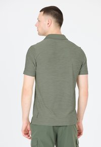Hør T-shirt til mænd i olivengrøn, lavet af tekstureret stof med et subtilt meleret mønster. Har klassisk krave og skrå slidser.
