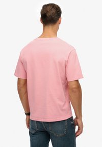 Lichtroze T-shirt met korte mouwen en een ronde hals, gemaakt van katoen, met een losse pasvorm en rechte zoom. Achteraanzicht weergegeven.