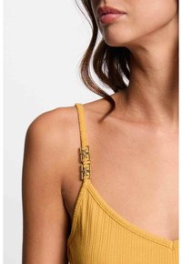 Mustard yellow ribbed tank top with thin straps. Features metallic square accent hardware on the left strap, textured fabric detail.