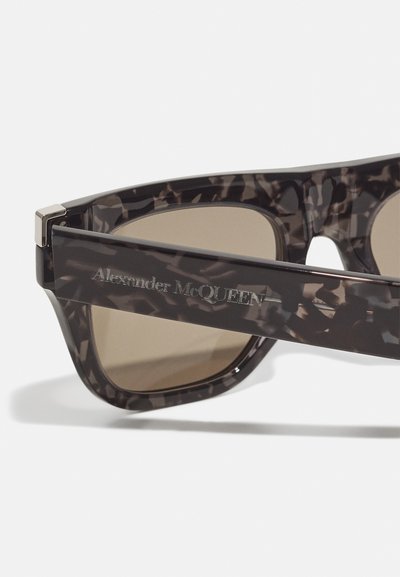 Schildpaddemønstrede solbriller med brune linser. Tykkere stel har et tekstureret mønster og en graveret brandlogo på stængerne. Metal detaljer medfølger.