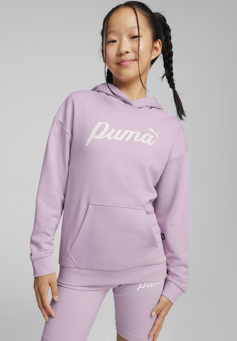 Sudadera lila con bolsillo canguro y logo blanco de "Puma", combinada con pantalones cortos lilas que presentan el mismo logo en la pierna. Textura de tela suave.