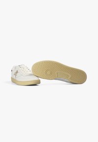 Zapatillas de cuero blancas con suelas de goma beige, que cuentan con un logo en el lateral, puntera redonda y un patrón de suela texturizado para mayor agarre.