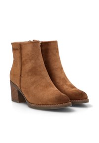 Botas de ante marrón hasta el tobillo con punta ligeramente afilada, cremallera lateral y tacón apilado. Textura suave con detalles de costura mínimos.