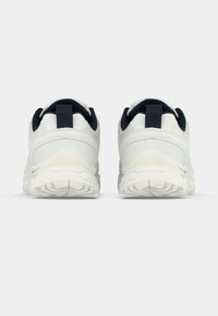 Balti sporta apavi ar teksturētu sintētisku augšdaļu, tumši zilu akcentiem, cilpām papēžos un rakstainu gumijas zolīti laba saķerei.