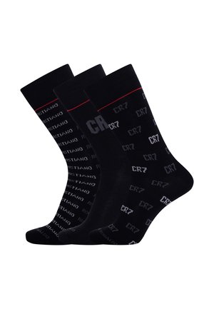 Trzy pary czarnych skarpetek za kostkę z powtarzającymi się białymi napisami "CR7" i "Cristiano Ronaldo" oraz cienką czerwoną linią blisko góry.