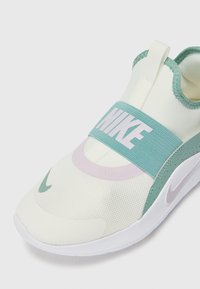 Nike Slipper-Sneaker mit oberem Teil aus cremefarbenem Stoff, mintgrünen Akzenten, pinkem kreisförmigem Detail und einem breiten elastischen Band mit "NIKE"-Branding.