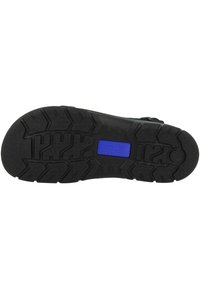 Black rubber shoe sole with a textured tread pattern, featuring a blue logo inset. Thick and durable design for traction.