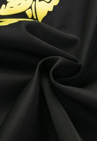 Schwarzer Stoff mit glatter Textur, der ein auffälliges gelbes Grafikdesign präsentiert. Das Material scheint leicht und haltbar zu sein.