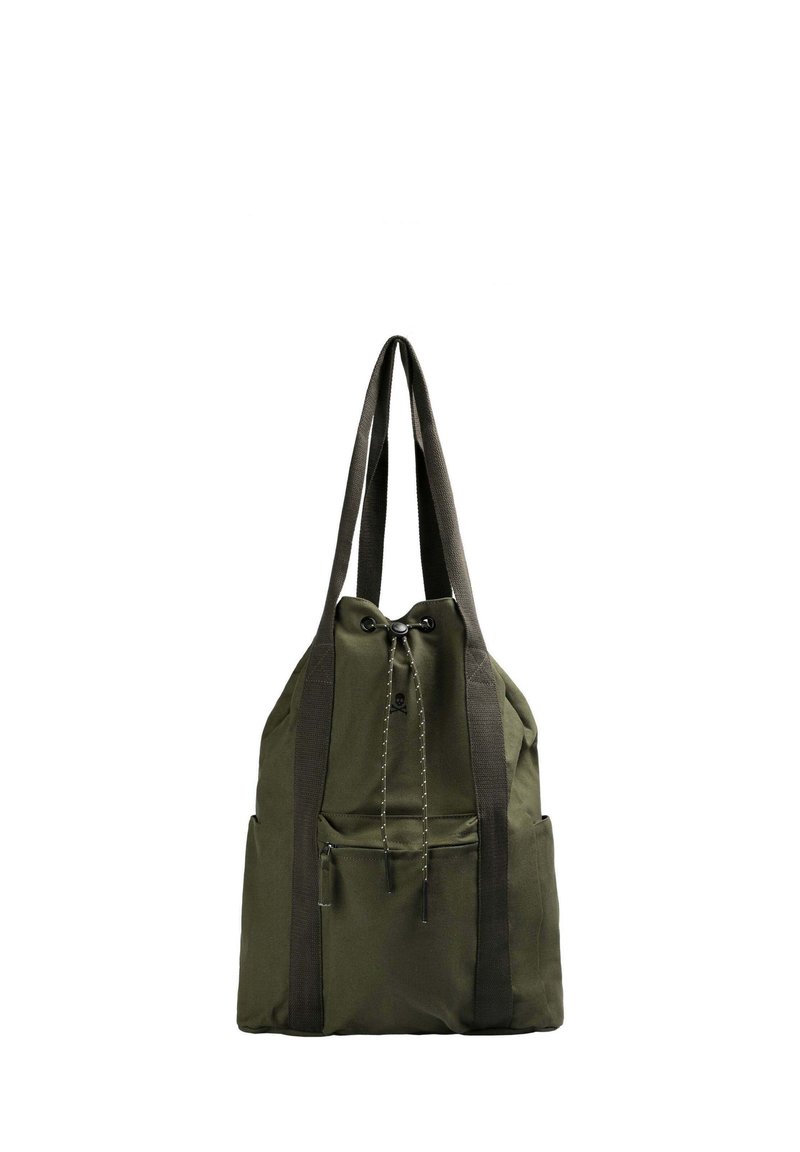 Mochila de tela verde con correas de webb negro, que cuenta con un cierre de cordón y un bolsillo frontal; diseño minimalista, textura suave.