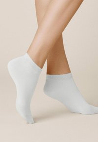 Weiße Knöchelsocken aus glattem Stoff. Sie verfügen über einen gerippten Bund und ein minimalistisches Design, das ein nahtloses Erscheinungsbild betont.