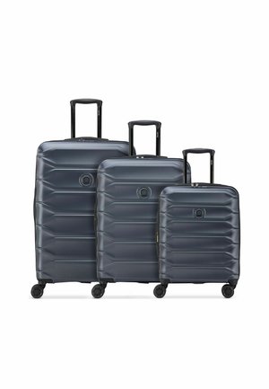 Trois valises rigides gris foncé de petite, moyenne et grande tailles avec des poignées extensibles et quatre roues chacune.