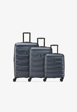 Trois valises rigides gris foncé de petite, moyenne et grande tailles avec des poignées extensibles et quatre roues chacune.