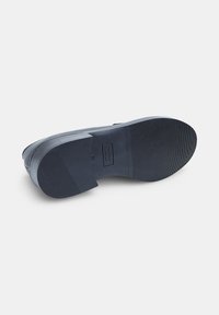 Talpă de pantof de culoare albastru închis, cu o suprafață texturată, având un toc pătrat și un logo. Designul este neted, cu o secțiune ușor ridicată la toc.