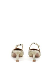Tacchi slingback metallici oro con una finitura liscia, tacco basso a blocco e cinturino alla caviglia. L'interno è di colore beige con dettagli di branding sottili.