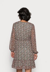 Květinové šaty z lehkého, průsvitného materiálu s dlouhými rukávy, přiléhavým pasem a volánkovým lemem. Obsahují barevné květinové vzory na tmavém pozadí.