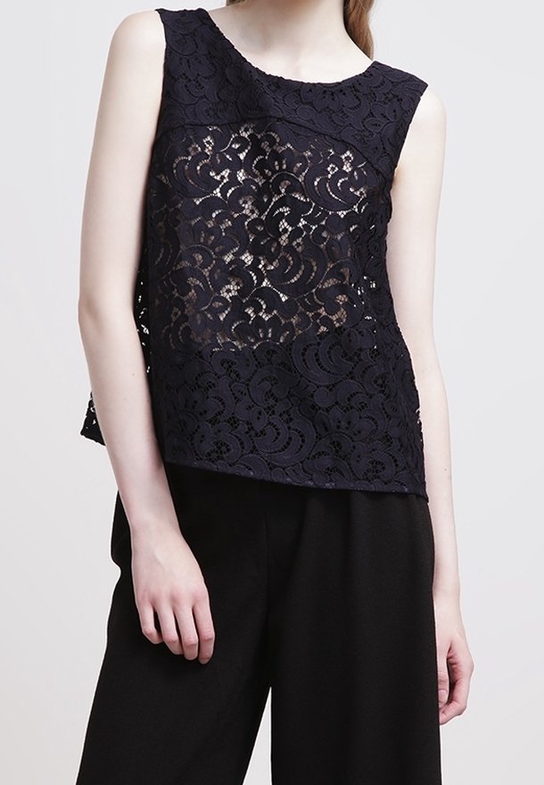 Navy lace top with sleeveless design, featuring floral pattern and sheer sections. Paired with high-waisted black trousers.