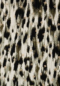 Tissu noir et crème à motif, avec une surface texturée, présentant des taches irrégulières et de subtils accents dorés tout au long.