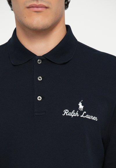 Tumši zilas krāsas polo krekls ar klasisku apkakli, trim pogām un baltu izšuvumu "Ralph Lauren" ar zirga emblēmu. Strukturēts audums.
