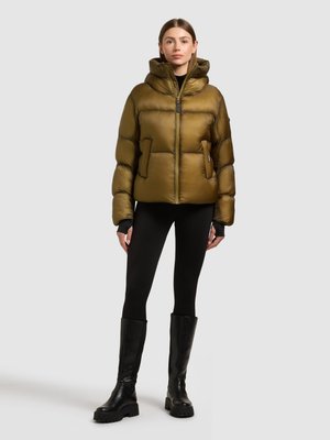 Olive green puffer jacket with a high collar and front zipper, featuring two side pockets and a textured finish. Paired with black leggings and knee-high boots.