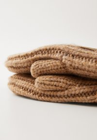Gants en laine marron tricotés avec une texture douce, présentant un design replié et des détails de couture visibles.