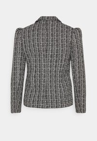 Sort og hvid tekstureret tweed-blazer med lange ærmer, strukturerede skuldre og skræddersyet pasform vist fra ryggen mod en neutral baggrund.