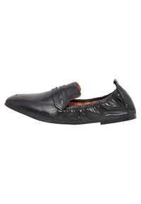 Zapato de cuero negro con un diseño aerodinámico, parte trasera elástica y estilo de calzado que se pone y quita fácilmente, con una correa frontal minimalista.