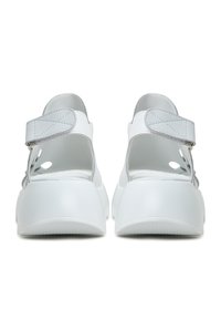White shoes with a smooth finish, back strap, and open sides. Features a thick, rounded sole and subtle gray accents.