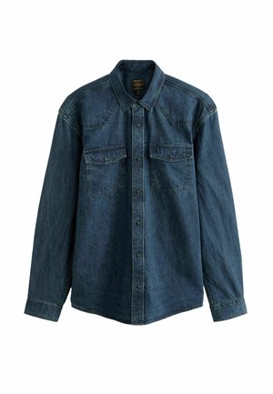 Denim shirt in dark blue, featuring long sleeves, a pointed collar, and two front pockets with snap button closures. Textured fabric.
