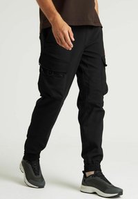 Pantalons cargo noirs avec plusieurs poches, poignets élastiques et coupe décontractée. Fabriqués en tissu durable, adaptés pour un usage quotidien et actif.