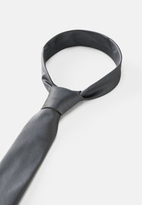 Corbata de seda gris con una textura suave, que presenta un patrón tejido y una forma clásica con un extremo estrecho y un nudo tradicional.