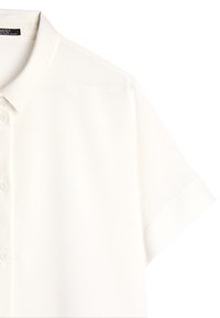Short-sleeve, white blouse with a classic collar and button placket. Smooth fabric with a slight sheen, featuring rolled cuffs.