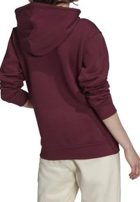 Bordeauxhed hoodie med en strukturerad huva, ribbade muddar och en avslappnad passform. Tyget verkar mjukt med en slät yta. Har ett elastiskt midjeband.