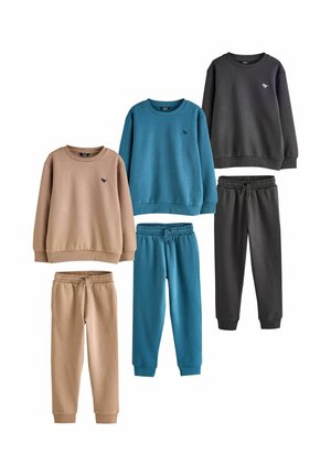 Trois ensembles de sweat-shirts pour enfants et de joggeurs assortis en beige, bleu et gris foncé, chacun avec un petit logo de dinosaure sur la poitrine.