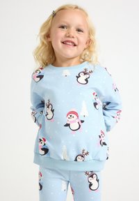 Light blue children's sweatshirt and pants set featuring playful penguin patterns, snowflakes, and holiday accents. Soft, comfortable fabric.